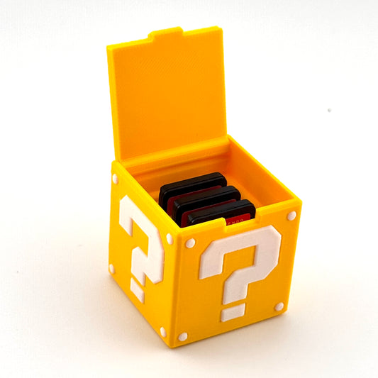 Open yellow cube-style game cartridge holder with a question-mark graphic and three compatible game cartridges