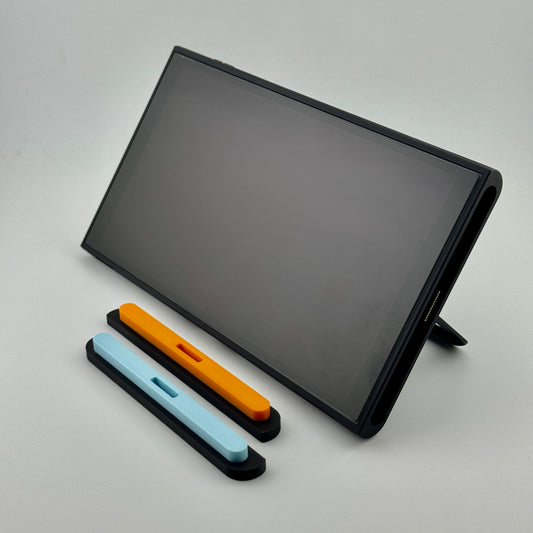 Nintendo Switch 2 tablet with personalizable magnetic controller-slot dust covers in orange and sky blue